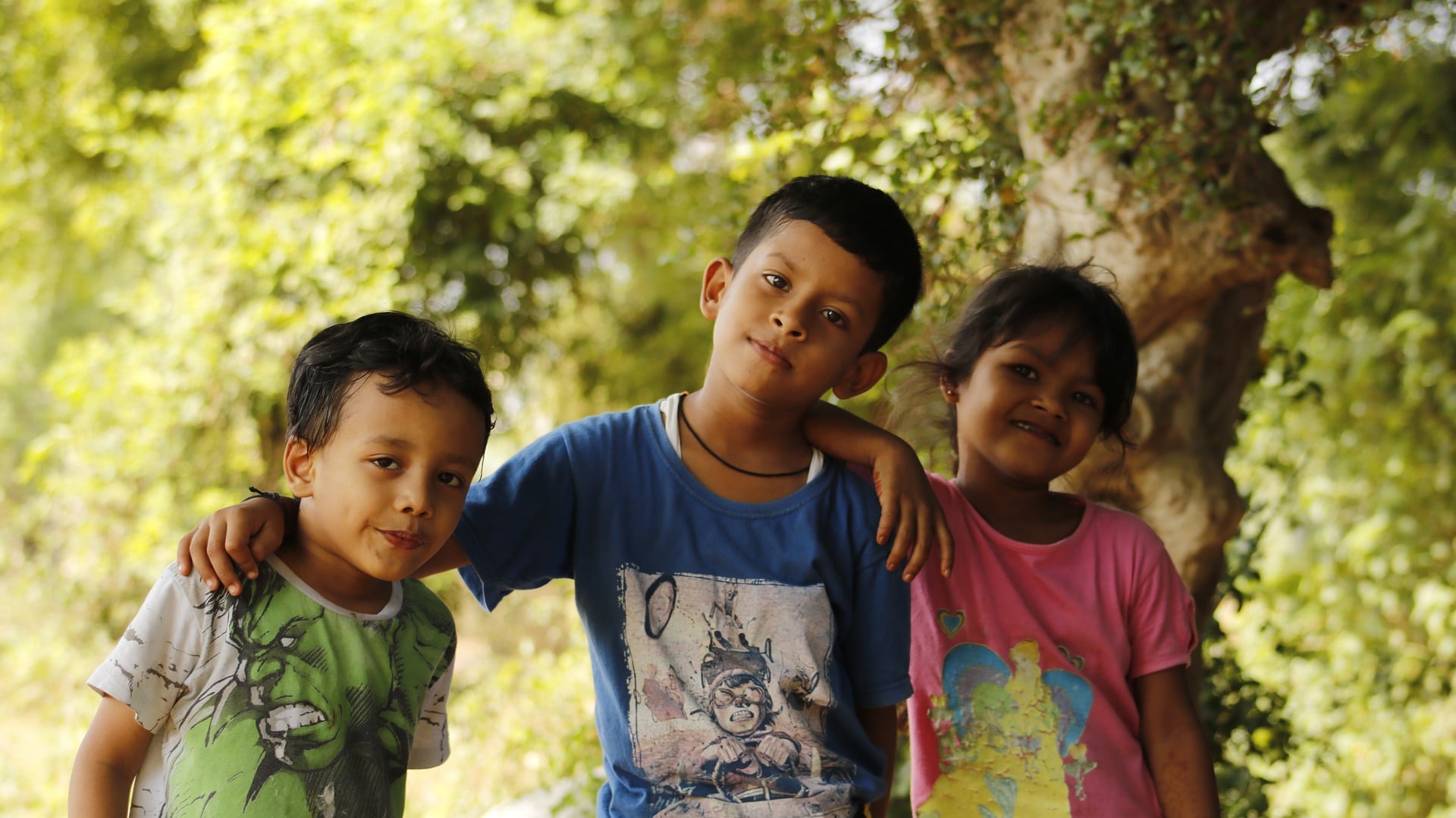 Dois meninos e uma menina em local arborizado. Imagem ilustrativa texto direitos de aprendizagem e desenvolvimento.