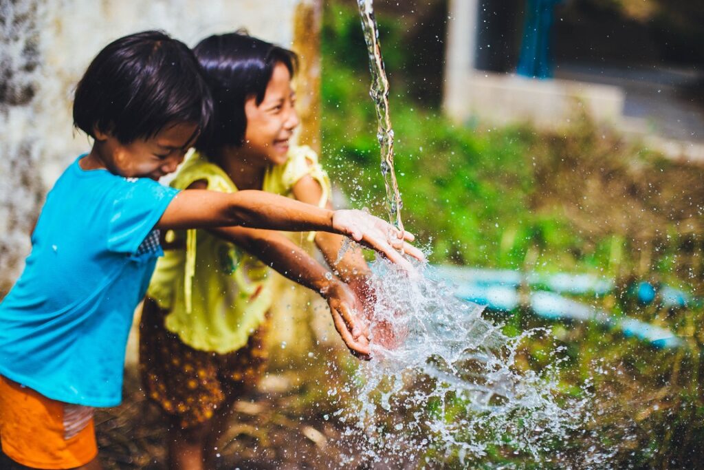 Crianças brincando com água. Imagem ilustrativa texto brincar no quintal.