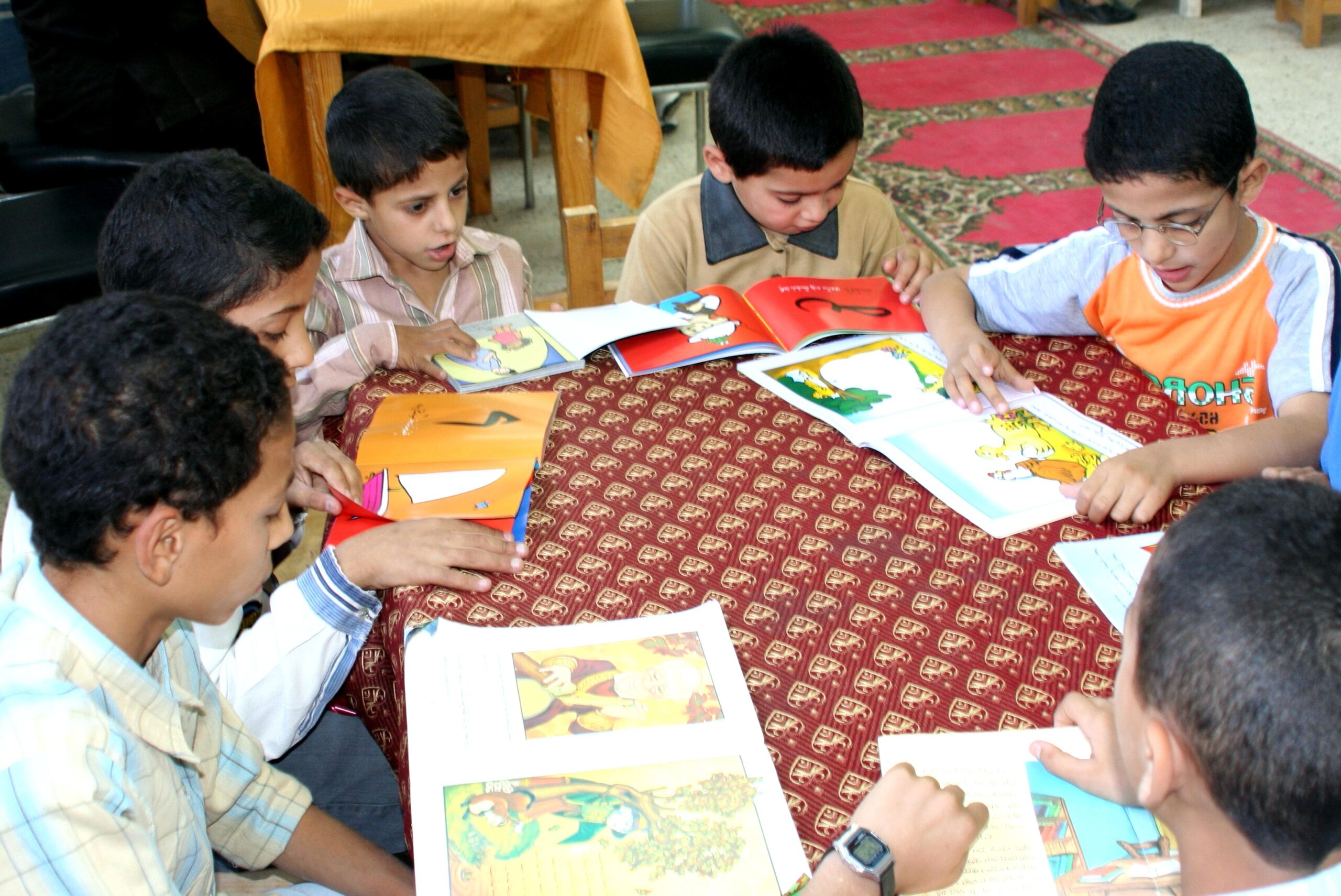 Meninos com livros infantis sobre a mesa. Imagem ilustrativa texto importância do livro infantil.