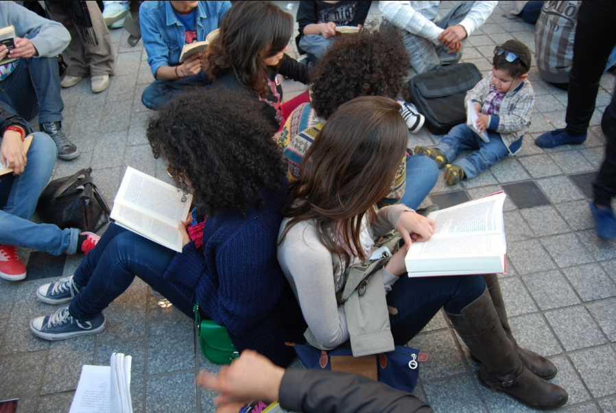 Adolescentes e crianças sentados no chão e lendo. Imagem ilustrativa texto diversidade literária.