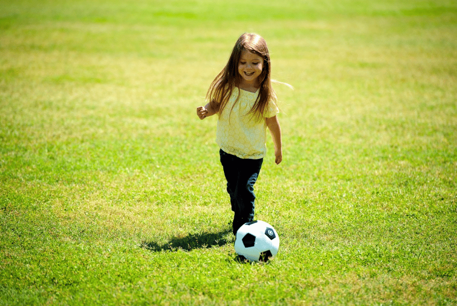 Menina jogando futebol. Imagem ilustrativa texto brincadeiras para queimar calorias.