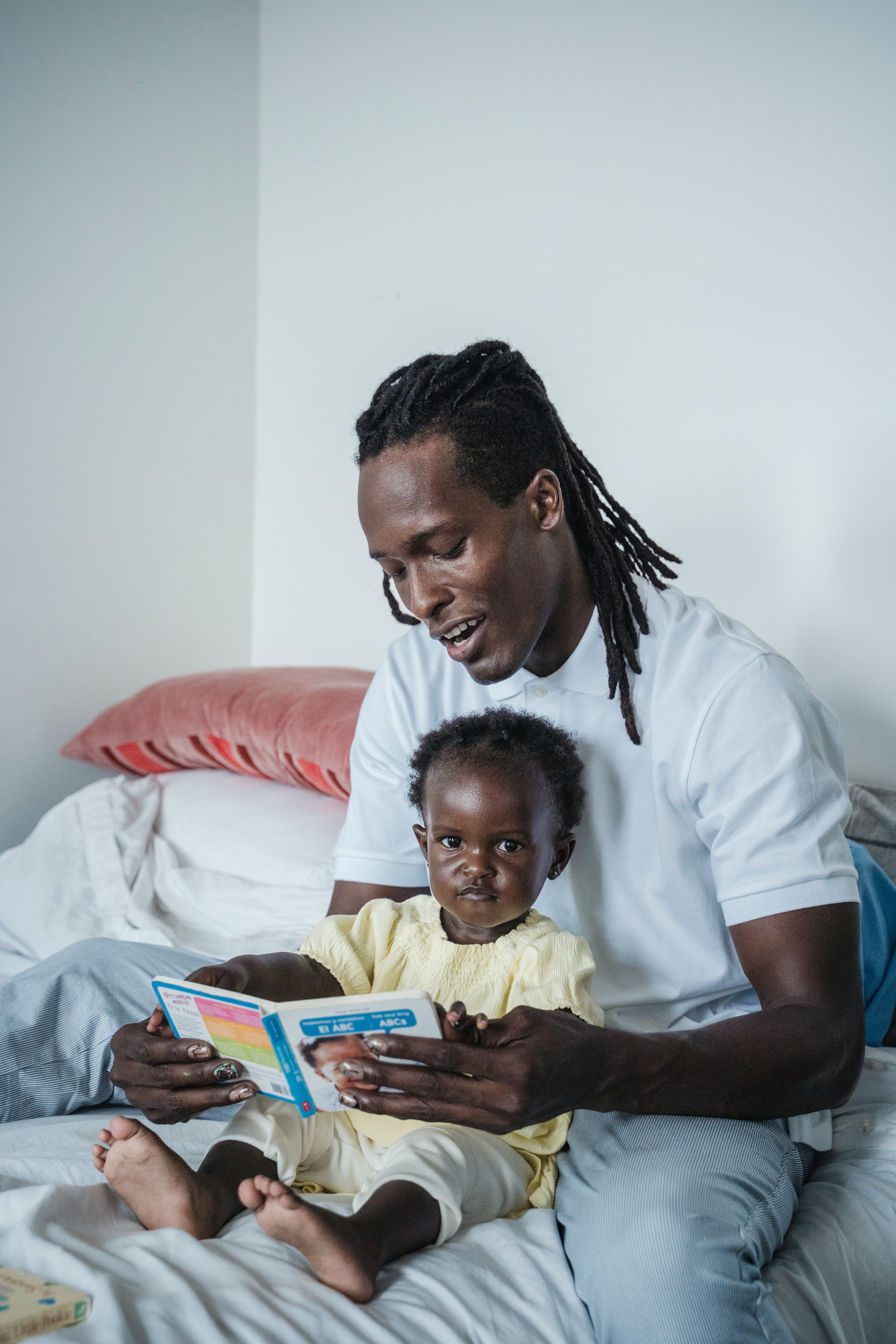 Pai com filho no colo, lendo livro. Imagem ilustrativa texto letramento.
