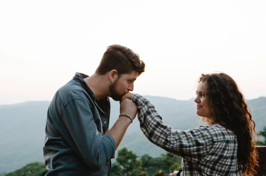 Homem beijando a mão de mulher em frente a paisagem. Imagem ilustrativa texto expressões tiradas da literatura.