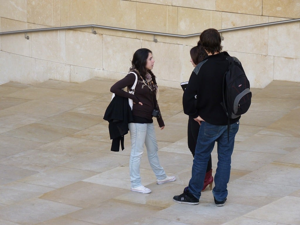 Três estudantes conversando em escadaria.