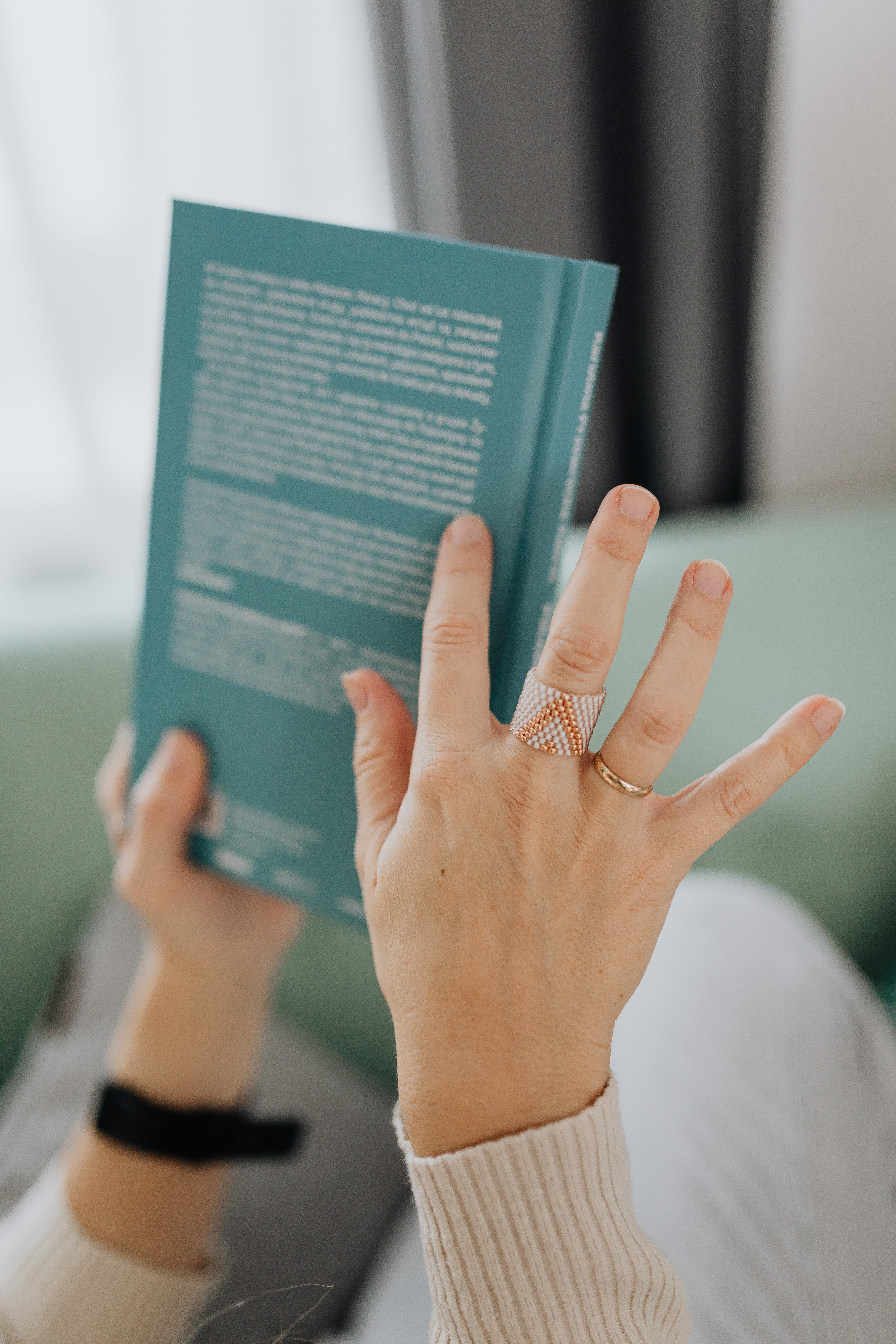 Mão de mulher lendo a contracapa de um livro.