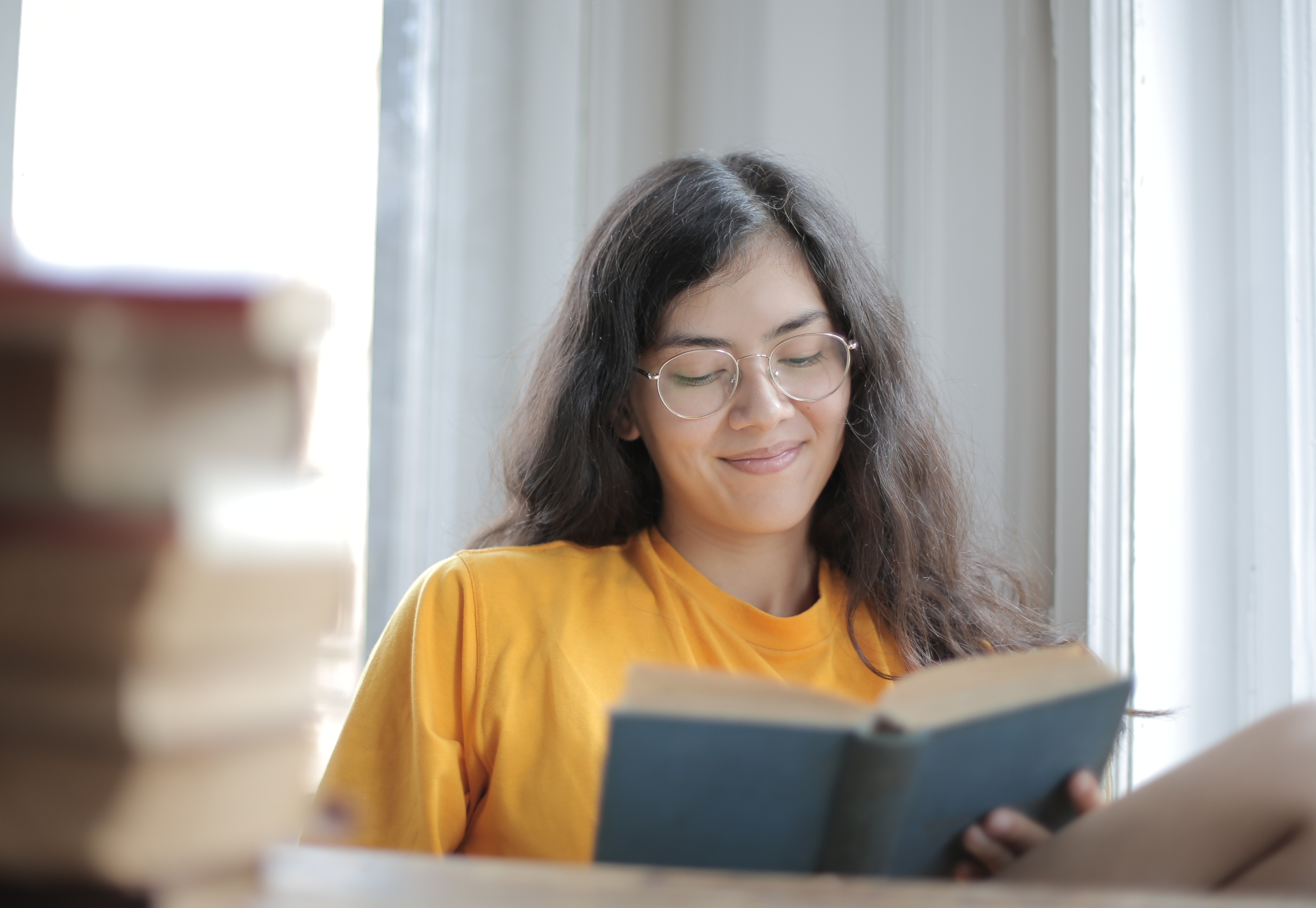 Mulher lendo livro e sorrindo. Imagem ilustrativa texto alívio cômico.